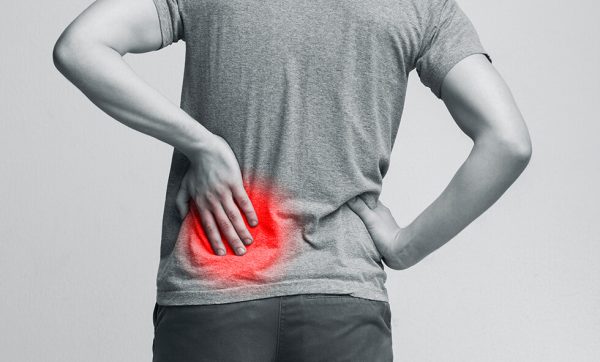 Black and white photo of a person touching a red area on their back indicating kidney pain